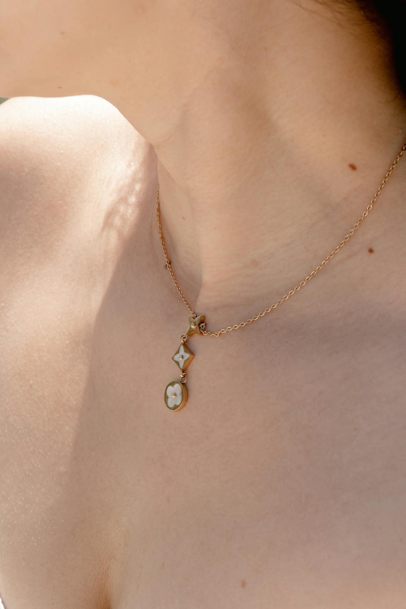 Close-up of a gold necklace on a woman's neck under sunlight, capturing elegance and simplicity.