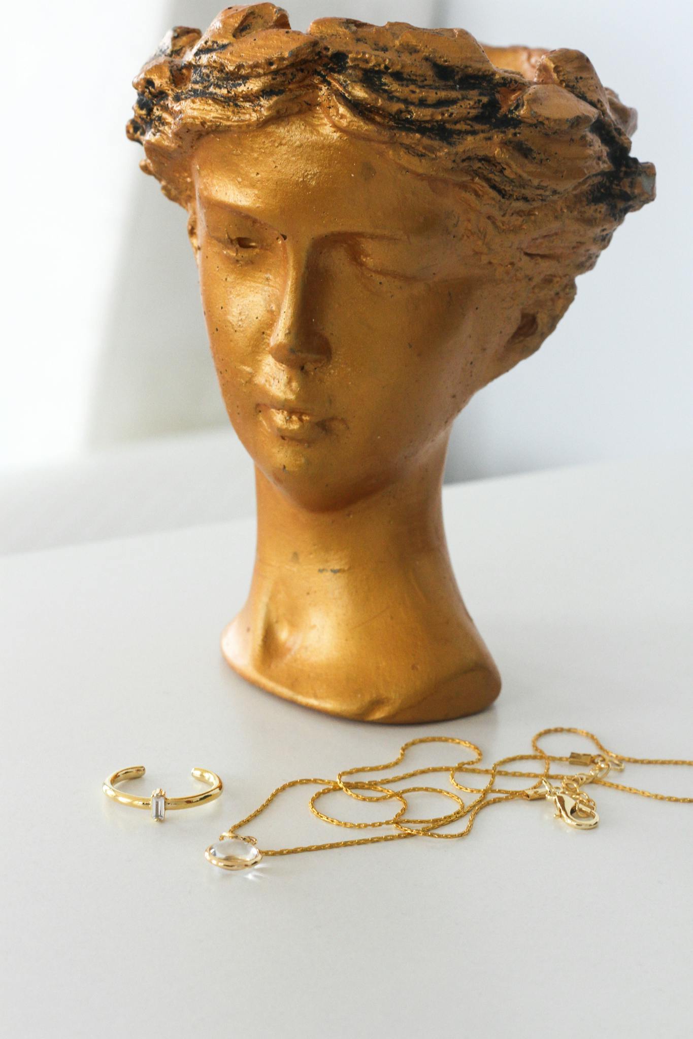 Close-up of a golden sculpture head with gold jewelry, creating an elegant decor piece.