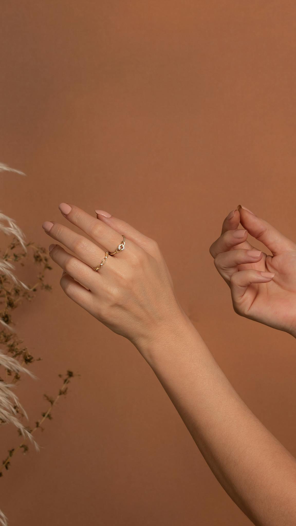 Showcasing minimalist gold rings on well-groomed hands against a warm background.